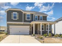 Charming two-story home with a covered porch, stone accents, a two-car garage, and a beautifully landscaped front yard at 5013 Dunsford Dr, Denver, NC 28037