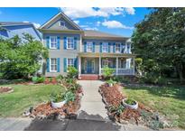 Charming two-story home with a landscaped yard, inviting front porch, and blue shutters on a sunny day at 1569 Benjamen Latrobe Cir, Fort Mill, SC 29708