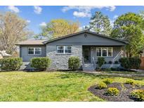 Charming single-story home with a well-maintained lawn and stone facade, set against a backdrop of mature trees at 1749 Archdale Dr, Charlotte, NC 28210