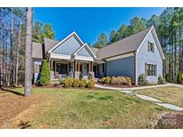 Charming blue home with a stone and wood columned front porch and beautiful landscaping at 188 Winding Forest Dr, Troutman, NC 28166