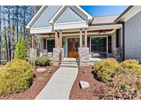 Charming home featuring a welcoming front porch with stone pillars and inviting wooden doors at 188 Winding Forest Dr, Troutman, NC 28166