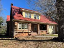 Charming brick home featuring a distinctive red metal roof and an attached garage, all set on a spacious lot at 521 Pee Dee Ave, Albemarle, NC 28001