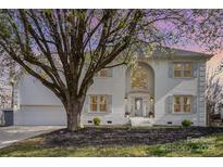 Elegant white brick home featuring a two-car garage, a manicured yard, and a beautiful tree at 6087 Diamond Pl, Harrisburg, NC 28075