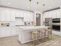 Modern white kitchen features a large island with seating, stainless steel appliances, and stylish pendant lighting at 8947 Nettleton Ave, Charlotte, NC 28215