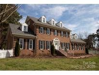 Charming brick home featuring dormer windows, black shutters, and landscaped front yard at 11215 Idlewild Rd, Matthews, NC 28105