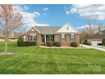 Charming brick home with a lush green lawn, manicured bushes, and a welcoming front entrance with black shutters at 205 Cowboys Cir, Rock Hill, SC 29732