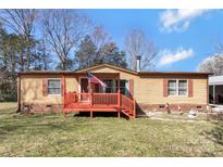 Charming tan home with a red porch, American flag, and mature trees on a sunny day at 3080 Sims Rd, Rock Hill, SC 29730