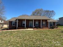 Charming brick home featuring a column-lined porch and manicured lawn on a sunny day at 3660 9Th Street Ne Dr, Hickory, NC 28601