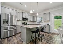 Modern kitchen boasts stainless steel appliances, grey cabinetry, and a granite island with seating at 117 Cramerton Mills Pkwy, Cramerton, NC 28032