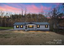 Charming single-story home featuring a welcoming front porch and a metal roof, set against a colorful sky at 118 Alfara Ln, Troutman, NC 28166