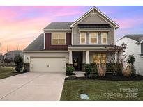 Charming two-story home with a well-manicured lawn, attached garage, and classic architectural details at 16839 Cozy Cove Rd, Charlotte, NC 28278