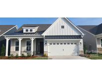 Charming home with a two-car garage, craftsman style porch, stone accents, and vertical siding detail at 324 Basil Dr, Indian Trail, NC 28079