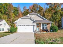 Charming home with a manicured lawn, stone accents, a cozy porch, and an attached two-car garage at 541 Settlers Grove Ln # 49, Salisbury, NC 28146