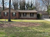 Charming single-story home with a brick facade, covered front porch, and attached garage at 8609 William Wiley Dr, Charlotte, NC 28215