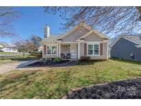 Charming single-story home with a well-maintained lawn, cozy front porch, and neutral siding at 114 Indian Paint Brush Dr, Mooresville, NC 28115