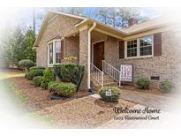 Charming brick home featuring a welcoming front porch and professionally landscaped yard at 1202 Ravenwood Ct, Salisbury, NC 28147