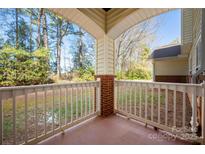 Inviting covered porch with brick detail and views of a wooded landscape, perfect for relaxing at 16312 Redstone Mountain Ln, Charlotte, NC 28277