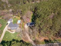 Aerial view of wooded property with home, pool, and detached garage at 7025 Ridgeway Rd, Stanley, NC 28164