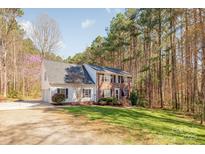 Charming two-story home with a well-manicured lawn, mature trees, and a three car garage at 7025 Ridgeway Rd, Stanley, NC 28164
