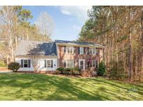 Charming two-story brick home with a well-manicured lawn and mature trees, creating a serene and inviting curb appeal at 7025 Ridgeway Rd, Stanley, NC 28164
