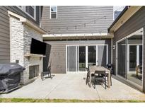 Outdoor patio with a stone fireplace, TV, grill, and dining set with a sliding glass door at 11327 James Coy Rd, Davidson, NC 28036