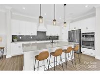 Bright kitchen features a large island with seating, stainless steel appliances, and modern pendant lighting at 11327 James Coy Rd, Davidson, NC 28036