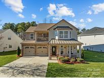 Charming two-story home featuring manicured lawn, covered porch, and attached two-car garage at 3181 Helmsley Ct, Concord, NC 28027