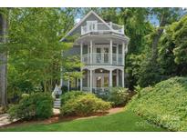 Charming home featuring a multi-level porch, detailed railing, and lush, mature landscaping surrounding the property at 545 Dilworth Mews Ct, Charlotte, NC 28203