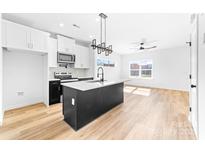 Bright kitchen features an island, modern light fixture, stainless steel appliances, and hardwood floors at 600 Legrand St, Shelby, NC 28150