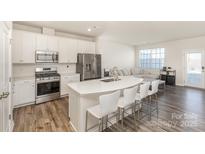 Modern white kitchen with island seating, stainless steel appliances, and open floor plan at 6048 Chelsea Oaks Rdg, Tega Cay, SC 29708
