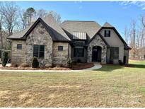 Charming home featuring stone and brick accents, complemented by a well-manicured lawn and mature trees at 1021 Mccollum Oaks Ln, Monroe, NC 28110