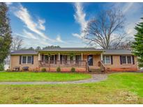 Charming brick home featuring a welcoming front porch and well-maintained lawn at 1115 Kelly Rd, Mount Holly, NC 28120