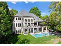 Stunning rear exterior featuring a pool, patio, and manicured lawn with a charming two-story balcony at 12014 James Jack Ln, Charlotte, NC 28277