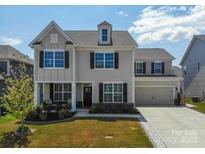 Charming two-story home with a well-manicured lawn, dormer, and attached two-car garage at 2010 Saddlebred Dr, Iron Station, NC 28080