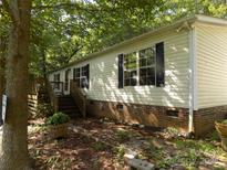 Charming home featuring brick foundation, black shutters, and inviting wooden deck at 2130 Babbling Brook Ln, Gastonia, NC 28052