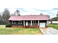 Charming single story home featuring dark siding, metal roof, a cozy front porch, and attached garage at 2180 Grace Church Rd, Salisbury, NC 28147