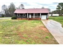 Charming single-story home features a red metal roof, covered porch, and attached one car garage at 2180 Grace Church Rd, Salisbury, NC 28147