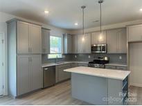 Modern kitchen featuring gray cabinets, stainless steel appliances, and a center island at 411 Sunharvest Ln, Indian Trail, NC 28079