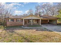 Charming single-story brick home with a covered front porch and a connected carport with a well-maintained lawn at 624 Flicker St, Concord, NC 28027