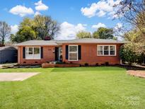 Charming brick home featuring a well-manicured lawn, classic shutters, and a welcoming facade at 836 E Woodlawn Rd, Charlotte, NC 28209