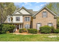 Charming two-story brick home with lush landscaping and a welcoming front porch and well manicured lawn at 8704 Dartmoor Pl, Mint Hill, NC 28227