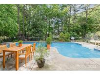 Relaxing pool area with a dining table and lush greenery creating a private oasis, perfect for outdoor entertaining at 8704 Dartmoor Pl, Mint Hill, NC 28227