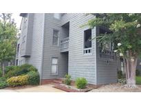 Charming condo exterior with gray siding, mature trees, and tidy landscaping, creating curb appeal at 9035 Jm Keynes Dr # 39, Charlotte, NC 28262