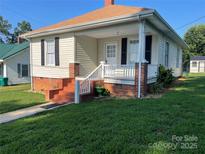 Charming home featuring a cozy front porch with brick accents and manicured lawn at 915 Spruce St, Albemarle, NC 28001