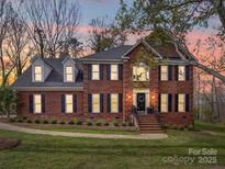 Charming two-story brick home with black shutters and a well-manicured lawn at sunset at 915 Waterview Ln, Monroe, NC 28110