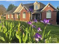 Charming brick home with manicured lawn and vibrant purple flowers in the front yard at 1308 Moonshadow Ln, Shelby, NC 28150