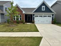 Charming single-story home featuring a brick and navy blue facade, attached garage, and manicured lawn at 1032 Barnette Farm Ln, Monroe, NC 28110