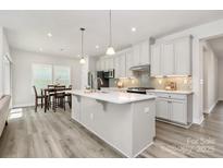 Bright kitchen features a large island, stainless steel appliances, pendant lighting and modern backsplash at 1032 Barnette Farm Ln, Monroe, NC 28110