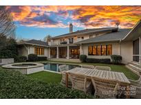Stunning backyard with a pool, spa, outdoor dining and a covered porch at a two-story home under a sunset sky at 19117 Davidson Concord Rd, Davidson, NC 28036