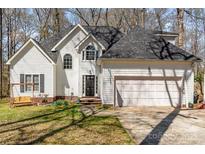 Traditional two-story home with a well-maintained lawn and a two-car garage in a wooded area at 2157 Mill House Ln, Matthews, NC 28104